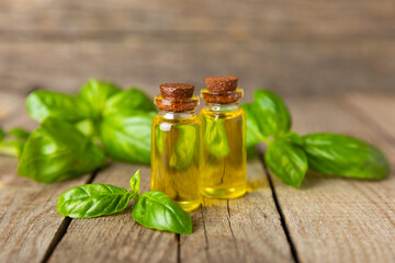 Basil essential oil on a textured wooden background. Basil essential oil and fresh leaves. Aromatherapy. Aroma oil. Medical herbs. Alternative medicine. Place for text. Copy space.