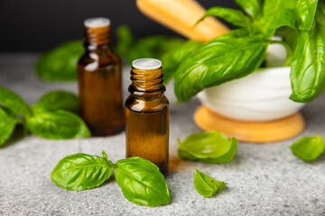 Basil essential oil on a textured wooden background. Basil essential oil and fresh leaves. Aromatherapy. Aroma oil. Medical herbs. Alternative medicine. Place for text. Copy space.