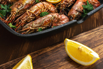 Fried shrimps on grill pan with fresh herbs and lemon slice. Seafood background.
