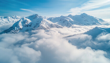 An aerial view captures a snowy mountain range enveloped by clouds under a vast sky