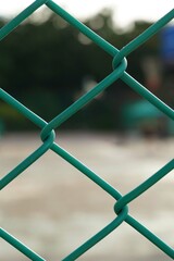 Close up a green net fence of the sports stadium back side blur people playing sports.