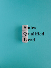 SQL - Sales Qualified Lead. Wooden cubes with words SQL. Beautiful blue background. Business and SQL concept.