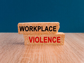 Concept red words WORKPLACE VIOLENCE on brick blocks. Beautiful blue background, wooden table....