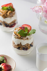 Yogurt with crispy granola, berries and mint leaves for a delicious breakfast. Healthy eating.