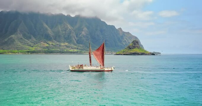 Following beautiful tropical sail boat in ocean near Hawaiian island - drone tracking shot