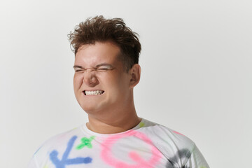 A young queer person with a colorful shirt smiles brightly.