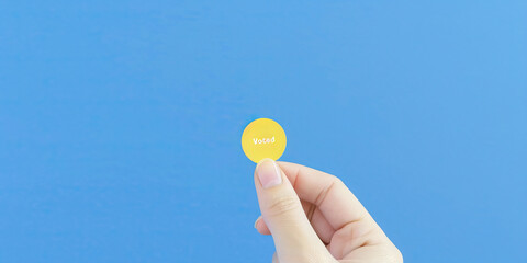 The Vote is Yours: A hand holding a "I Voted" sticker, ready to be affixed after a successful trip to the polls