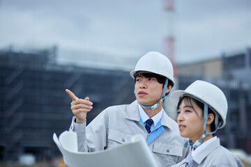 建設現場を視察するヘルメットを被り作業服を着たビジネスマンとビジネスウーマン