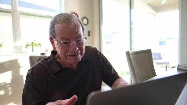 senior citizen shaking his head and smiling in agreement when looking at an article on the internet from his computer