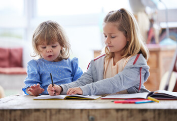 Fototapeta premium Children, writing and notebook together in home, education and learn with sister or child development or growth. Bonding, drawing and pencil on paper for sketch, creative skills and girl in apartment