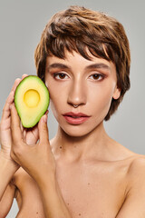 Woman playfully holds avocado in front of her face.