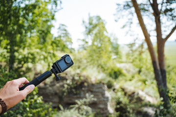 Immersing in the beauty of nature while using an action camera to capture outdoor adventures in a lush forest with stunning scenery and greenery, creating cherished memories