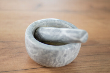 Light stone kitchen mortar and pestle on a wooden table.