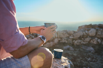 Man enjoying mountain view with coffee, relaxing outdoors, and embracing scenic inspiration