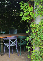 Painted vintage chairs and table under canopy in garden. Nature and recreation. Country plot in summer. 