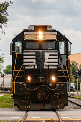 Front view of a freight train with lights on.