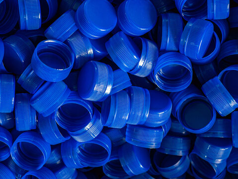 Top view blue plastic bottle caps.Recycling collection and production processing plastic bottle caps background ,Industrial production of bottle caps made of blue high-density polyethylene.