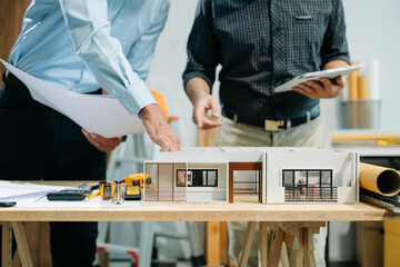 Two colleagues discussing data working and tablet, laptop with architectural project at construction site