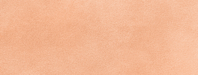 Color year 2024 peach fuzz. Light coral matte background suede fabric. Velvet texture of textile,