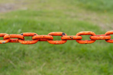 Red chain with green grass in background.  Photo from Westfjords in Iceland.