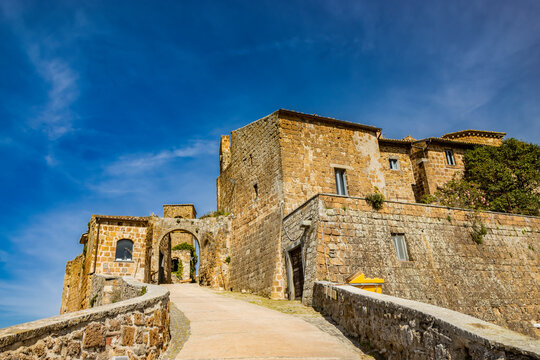 A glimpse of the ancient medieval village of Celleno, Viterbo, Italy. Ghost town, with houses in ruins, abandoned and uninhabited. The castle walls and the road with the arch leading to the town.