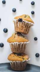 stack up blueberry muffins/cupcakes on a white background with fresh blueberries. 
