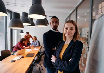 Dynamic Leadership Duo: Blonde Director and Young African American Entrepreneur in Office Setting.