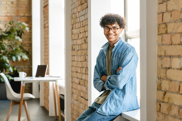 Handsome mixed-race young man having rest at his workplace in office. Afro american boy guy...