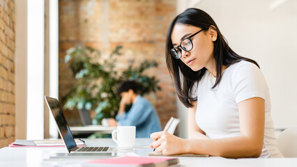 Busy smart young asian girl student marketing smm manager social media worker freelancer intern businesswoman working remote distant studding in office desk in coworking space. College education