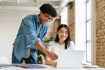 Two young business partners colleagues friends students classmates working studding together...