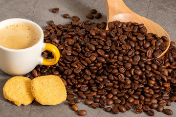 An espresso with foam, some biscuits and coffee beans and the wooden spoon to pick them up.