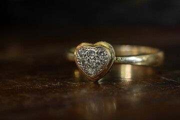 Closeup of tarnished, heart-shaped gold ring with diamonds