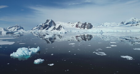 Melting Antarctica ocean landscape in polar summer. Snow covered mountains, blue sky in sunny day. Explore Arctic wildlife. Ecology, climate change and global warming concept. Aerial rotation panorama © mozgova