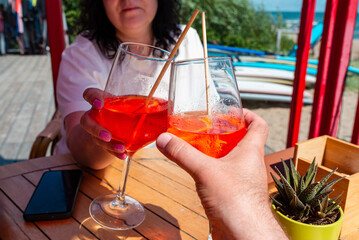 Middle-aged couple drinking spritz aperol in summer outdoor cafe.