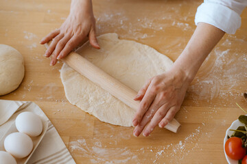 woman's hands kneading dough on the kitchen table
