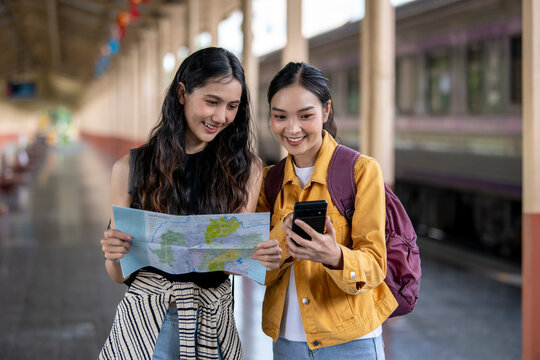 Two women are looking at a map and one of them is holding a cell phone