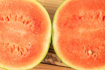 Two halves of a juicy watermelon, macro, on a wooden table, top view.