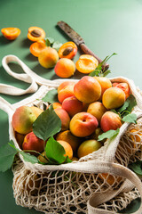 Ripe apricots in a string bag on a single background