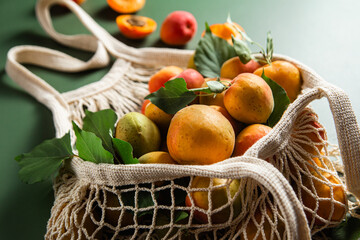 Ripe apricots in a string bag on a single background