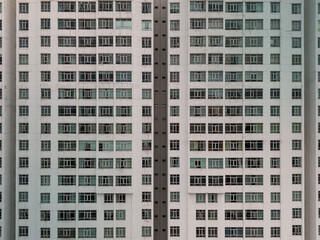 Obraz premium Massive hi rise residential building facades aerial view in vertical format. Symmetrical, geometric details of housing development of tower shot during the day.