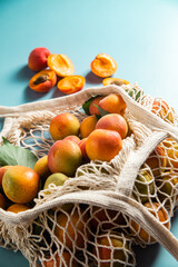 Ripe apricots in a string bag on a single background