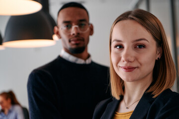 Dynamic Leadership Duo: Blonde Director and Young African American Entrepreneur in Office Setting.
