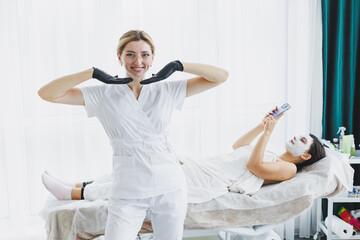 A cosmetologist wearing glasses and gloves performs a facial care procedure on a patient. A...