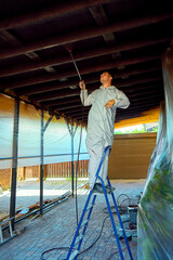 Fototapeta premium man paints a room with a spray gun
