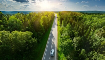Fototapeta premium Aerial view of car driving on asphalt highway road in green forest. Sun shine. Travel concept. Generative AI
