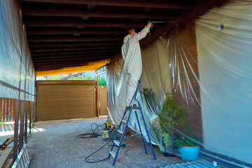 man paints a room with a spray gun