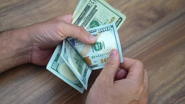Business owner counts pack of dollar banknotes considering allocating funds towards purchasing inventory and covering operational costs to sustain growing business