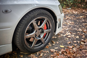 White car's wheel on a street background. Modern city sport car wheel wallpaper