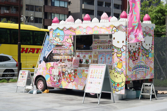 TOKYO, JAPAN - July 21, 2024: A truck selling Hello Kitty and other Sanrio ice creams, donuts, and other sweets and goods. It's in Tokyo's Ginza area. There is a Hato tour bus on the adjacent road.