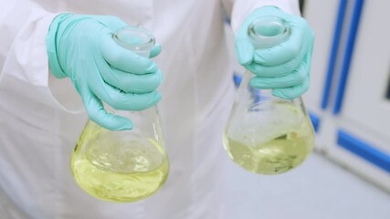 Chemist shaking yellow samples of urine before conducting biochemical analysis